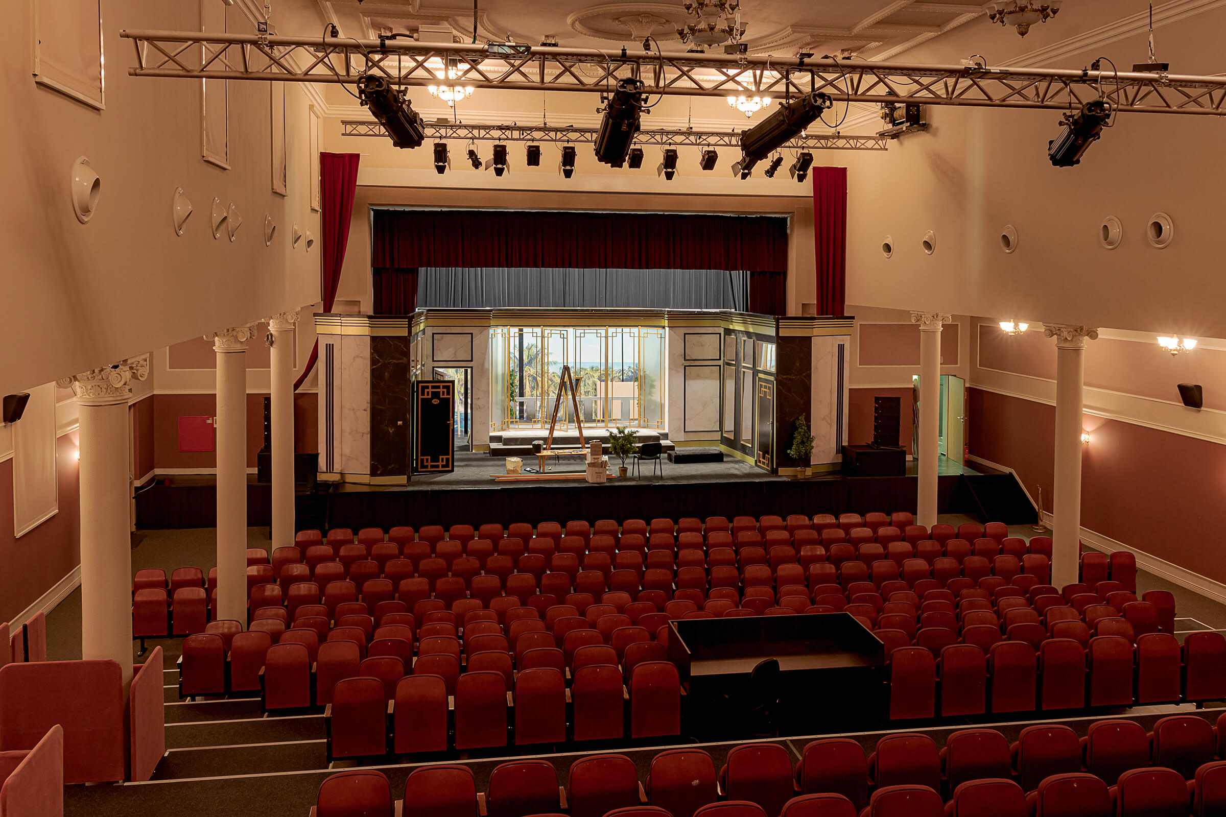 Sala widowiskowa z wygodnymi fotelami Na drugim planie scena z przygotowaną scenografią teatralną.