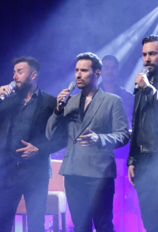 trzech śpiewających mężczyzn, w tle gitarzysta i basista